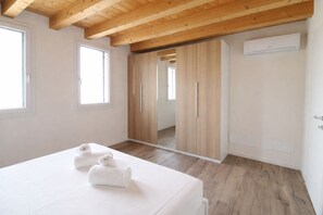 Ein Schlafzimmer mit einem Bett, zwei Handtüchern, einem Kleiderschrank und einer Klimaanlage.