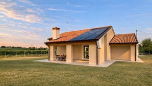 Una casa con techo solar, una chimenea y un patio con mobiliario exterior.