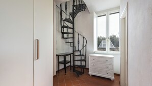 A corner room with a spiral staircase, a white dresser, and a window with a view. - Fossi Panoramic Terrace by MMega (Florence)