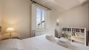 A bedroom with a bed, a window, a bedside lamp, a radiator, and a bookshelf. - Fossi Panoramic Terrace by MMega (Florence)