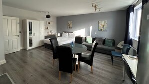 Ein modernes Zimmer mit einem Bett, einem Esstisch und einem Sofa.