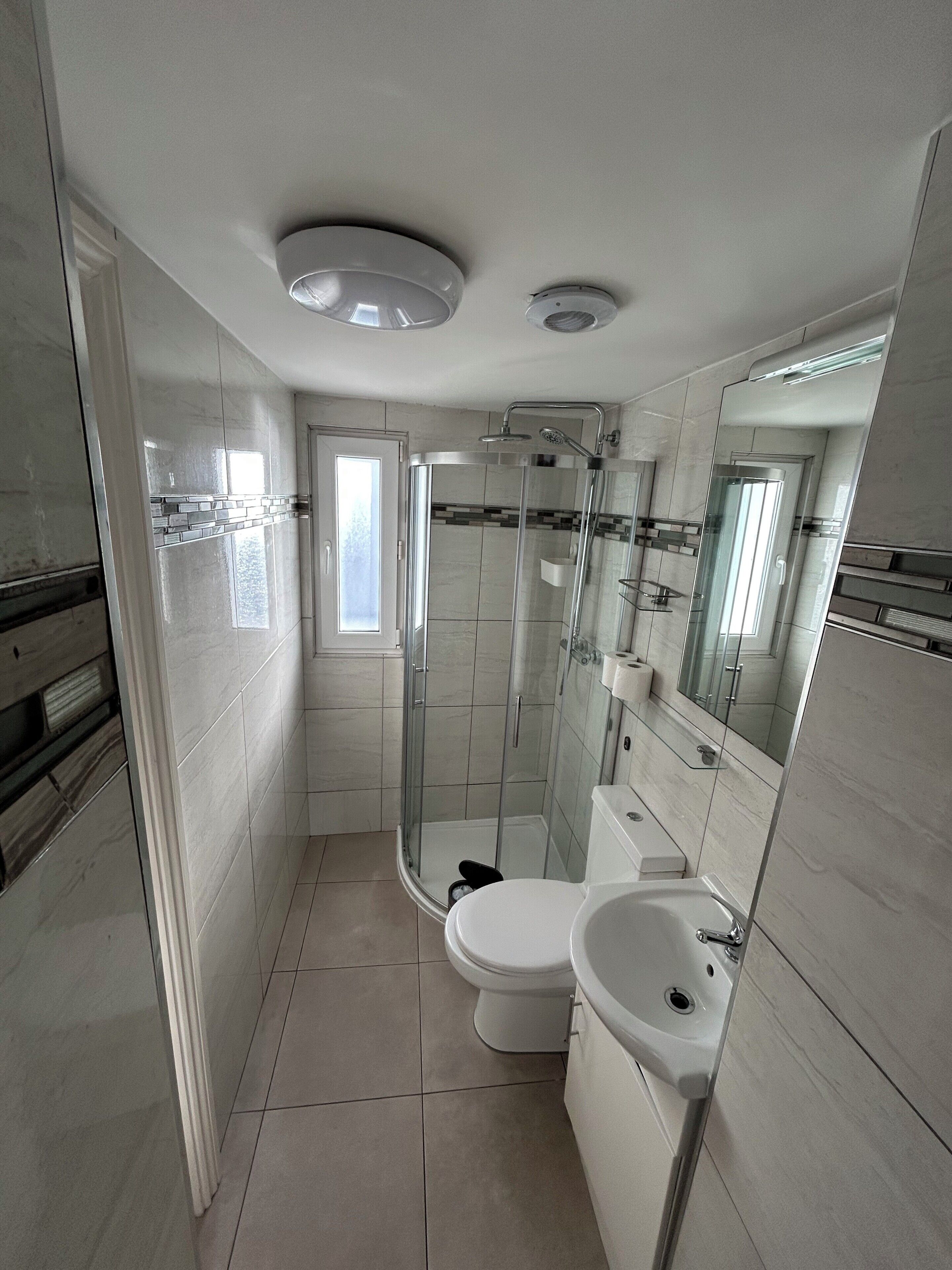 A modern bathroom with a glass-enclosed shower, a toilet, and a sink.