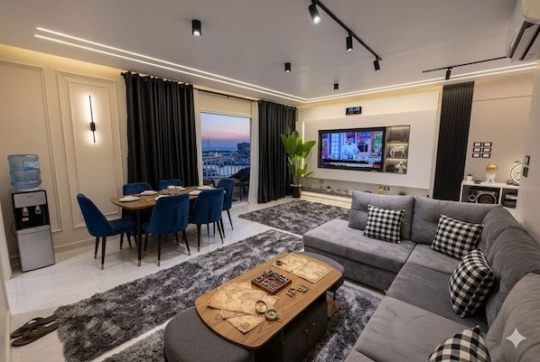 Ein modernes Wohnzimmer mit einer Couch, einem Esstisch und einem Fernseher.