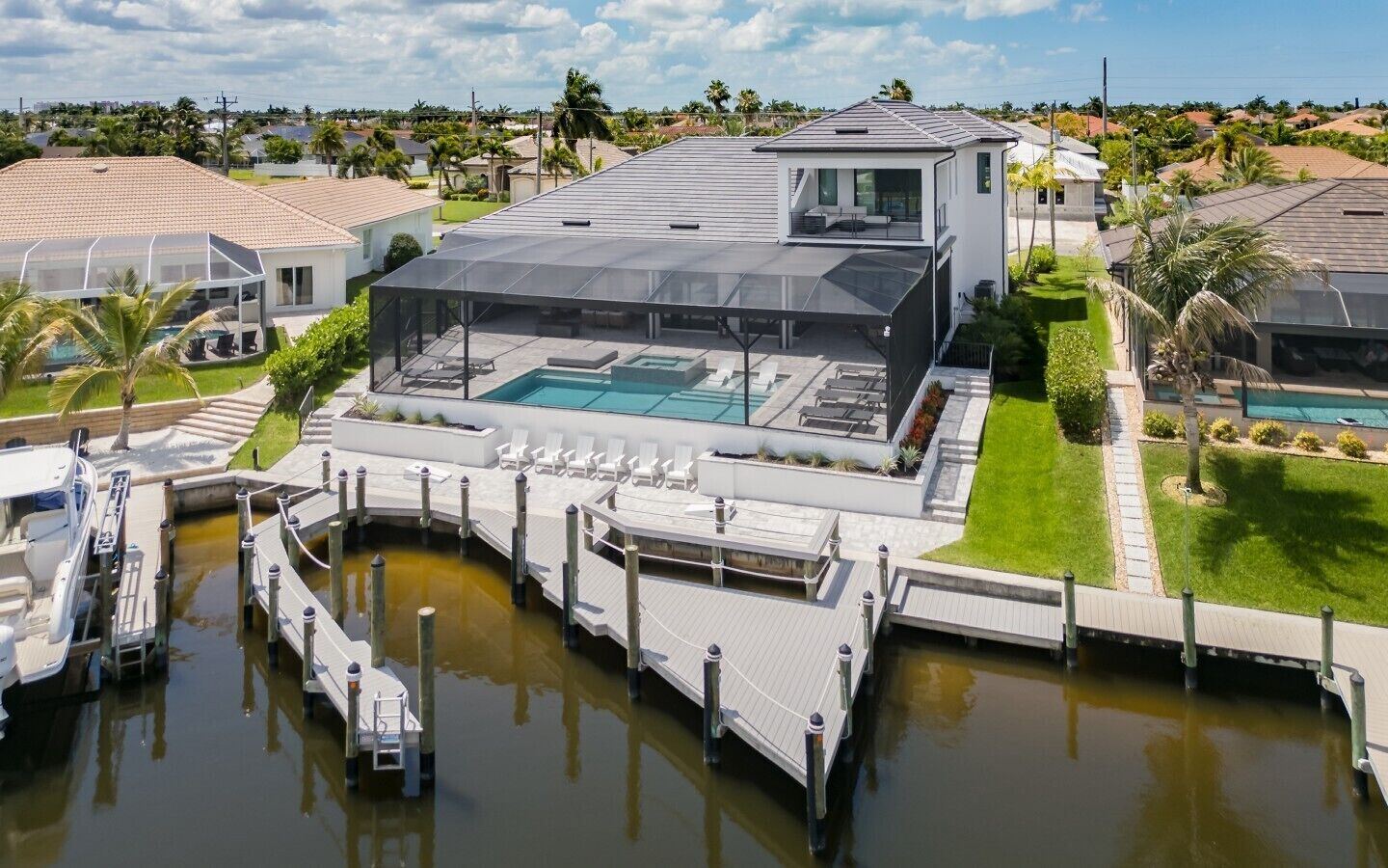 A modern house with a swimming pool, dock, and surrounding greenery.