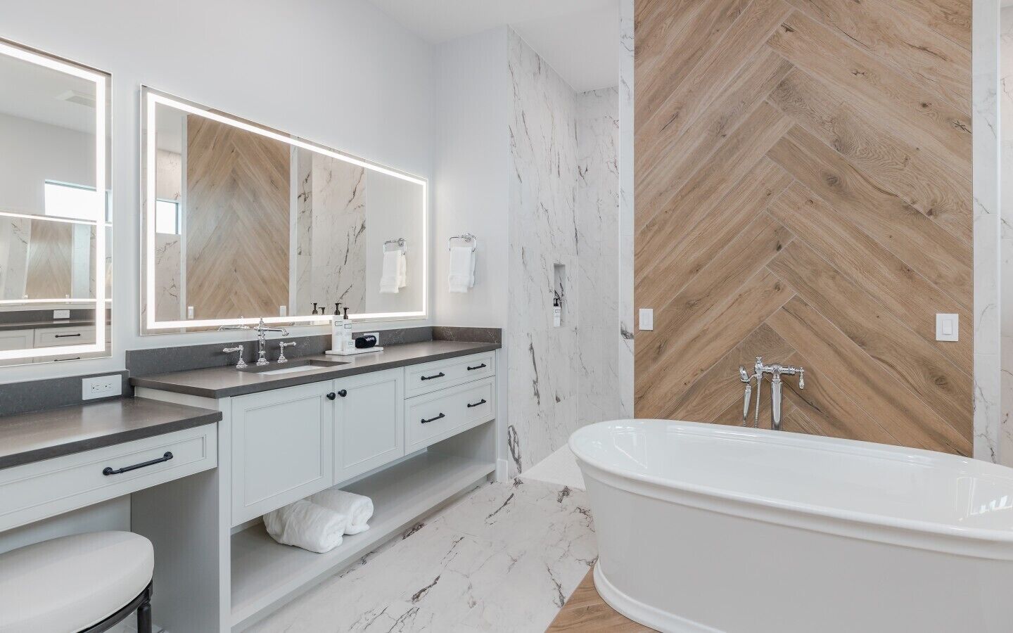 Une salle de bain moderne avec une baignoire sur pieds, un meuble-lavabo avec un miroir et un mur en bois disposé en motif chevrons.