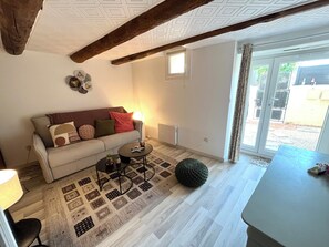 Un salon avec un canapé, une table basse et un pouf en tricot.