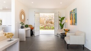 A modern interior with a reception desk, seating area, and a view of a garden through an open door. - Amara 4 - Luxury villa with sea view (Les Trois-Îlets)