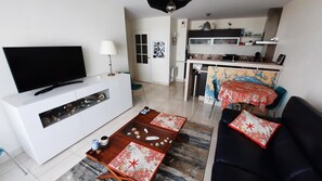 Una sala de estar con televisor, sofá, mesa de centro y un comedor con mesa y sillas.