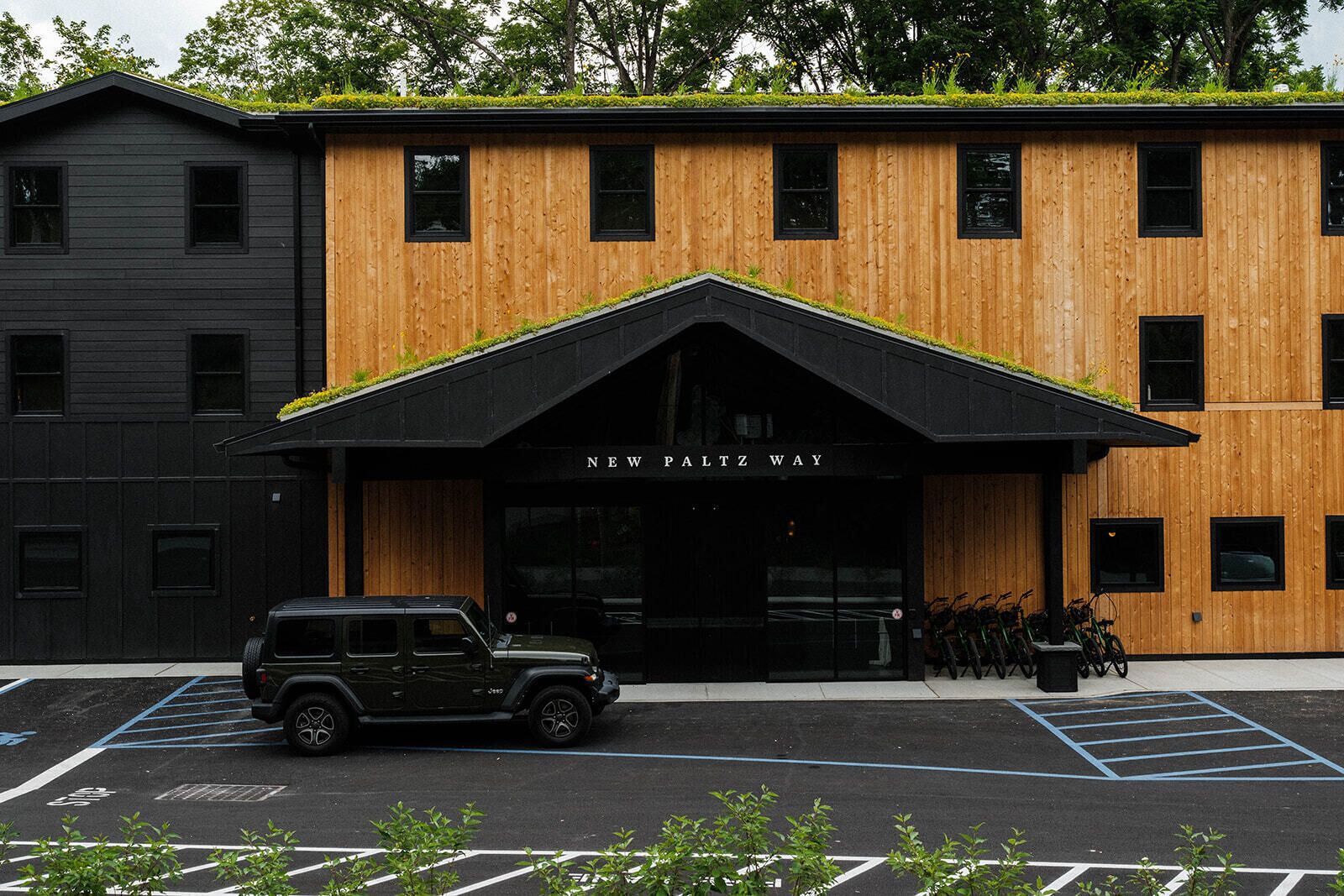 A building with a black and wooden facade, a black awning, and a sign reading 'NEW PALTZ WAY'.