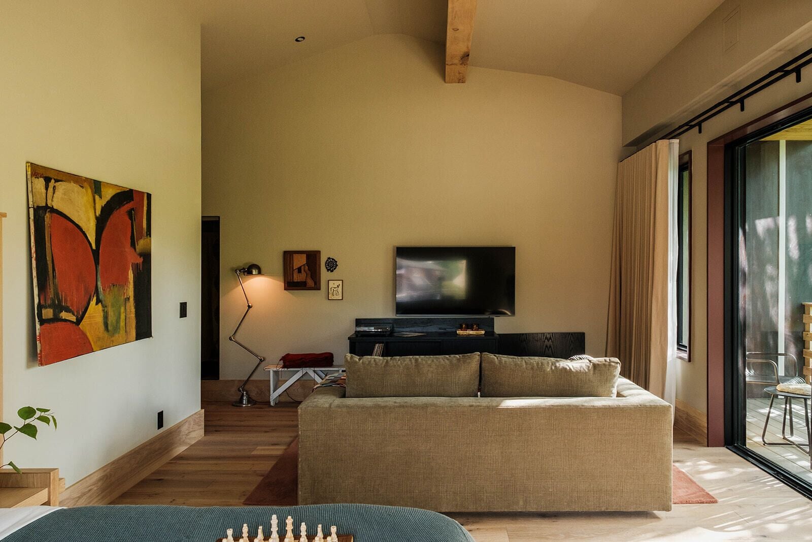 Un salón espacioso con un televisor de pantalla plana grande, un sofá, un tablero de ajedrez y un cuadro en la pared.