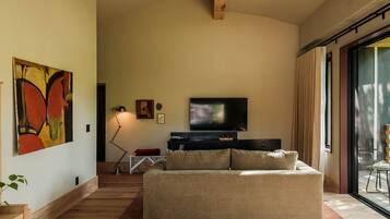 A spacious living room with a large flat-screen TV, a sofa, a chessboard, and a painting on the wall.