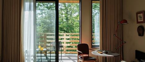Habitación de hotel con cama, una silla, una mesita, una lámpara y vistas al exterior.