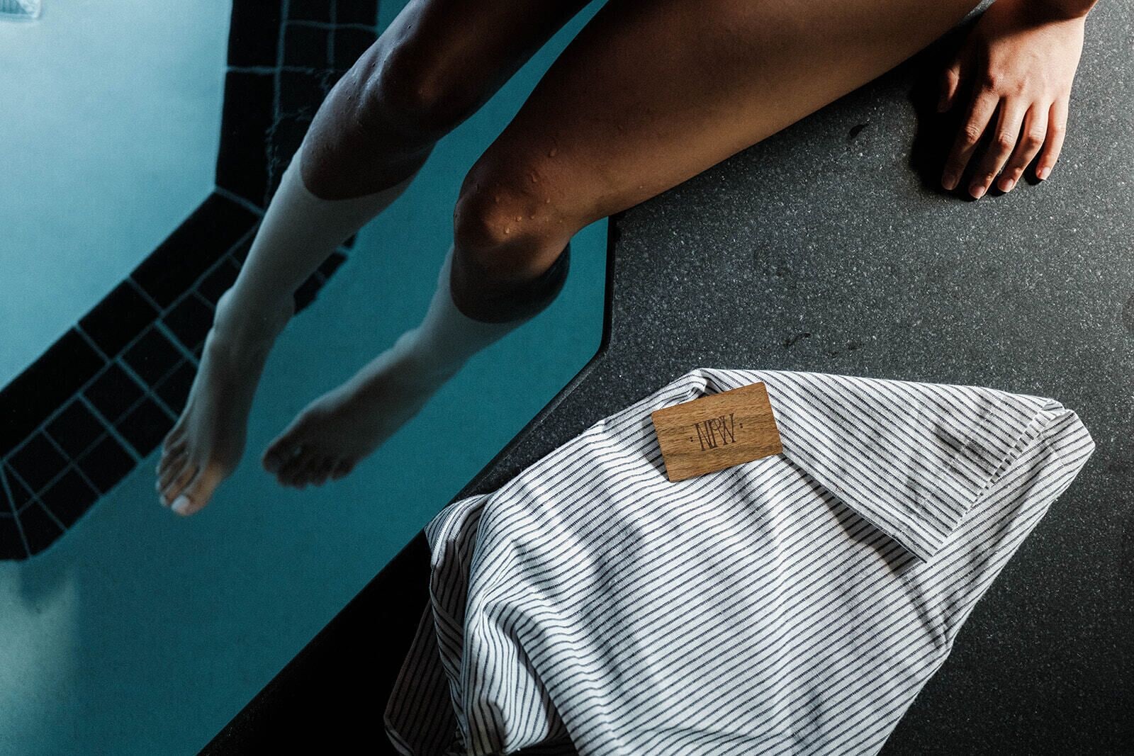 A person in a swimming pool with a striped towel and a wooden tag on it.