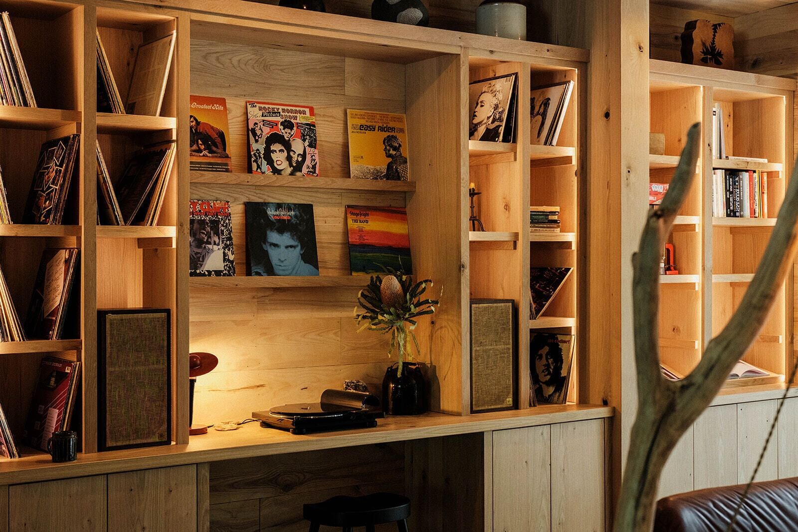 A wooden bookshelf with vinyl records, books, and framed pictures.