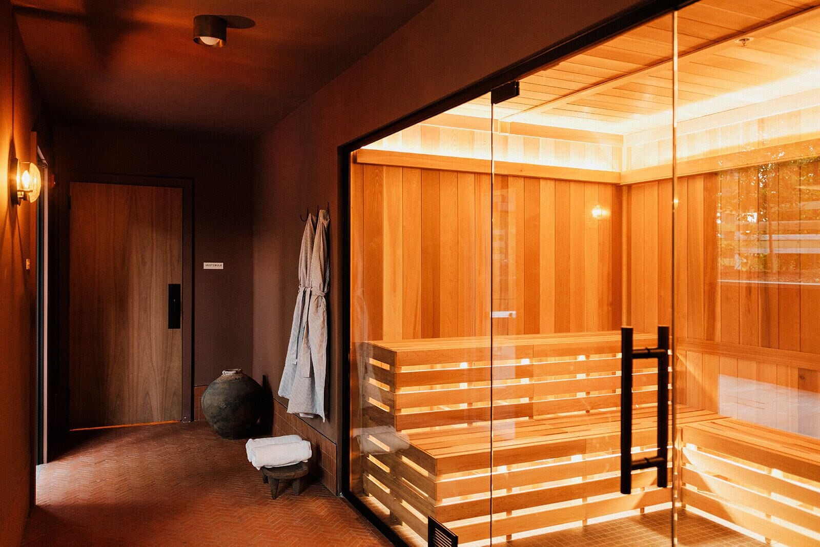 Una sauna con panche in legno e una porta in vetro.