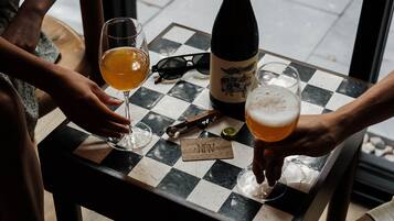 A checkered table with a bottle and glasses of beer, a pair of sunglasses, and a corkscrew.