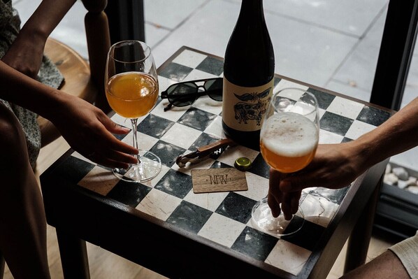 Une table à carreaux avec une bouteille et des verres de bière, une paire de lunettes de soleil et un tire-bouchon.