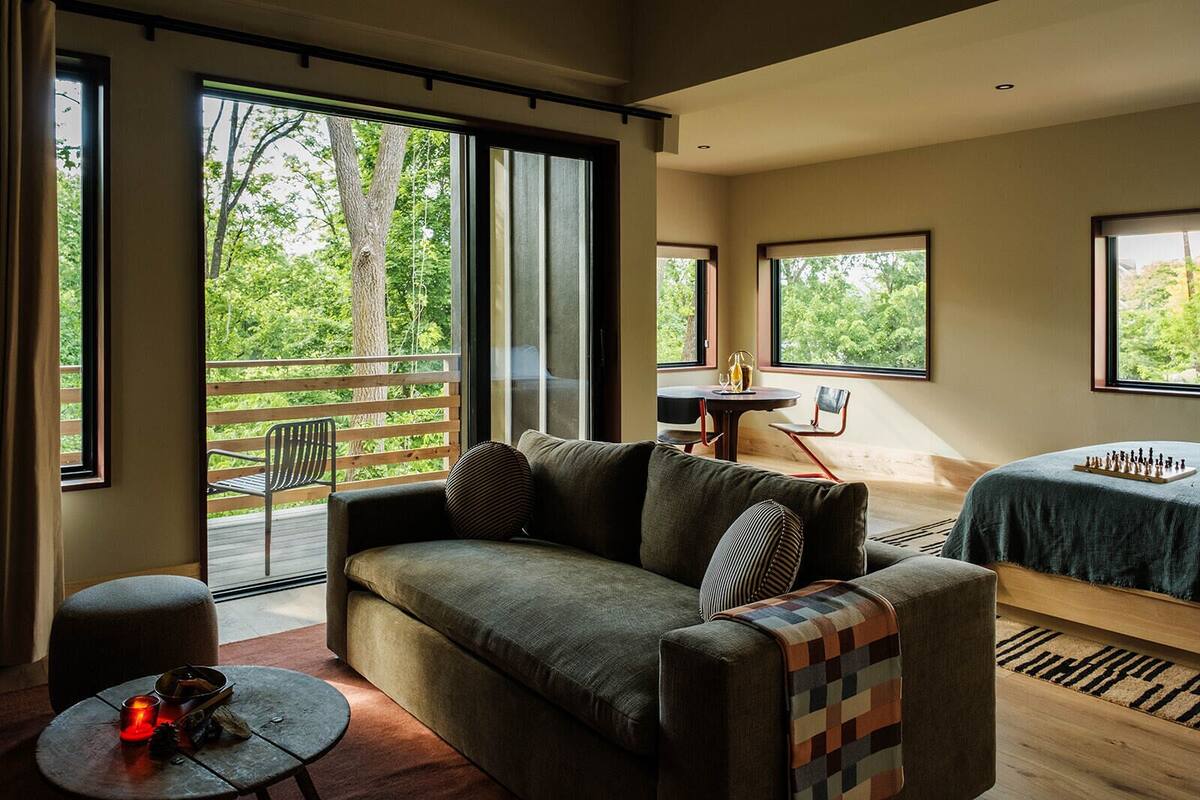 A modern room with a sofa, a small table with a candle, and a chessboard on a bed.