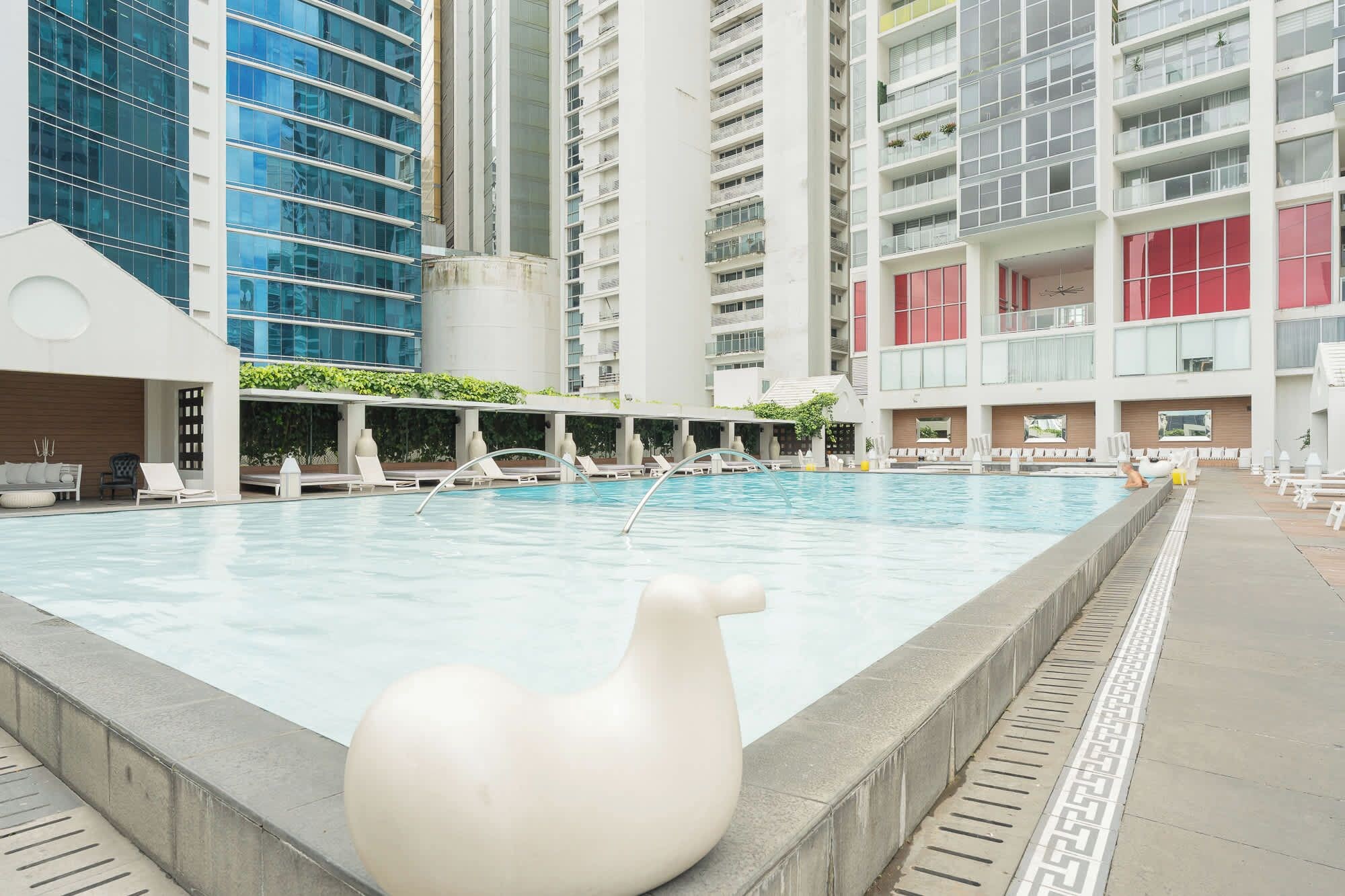 Una piscina interior con sillones de descanso y una gran escultura blanca al frente.