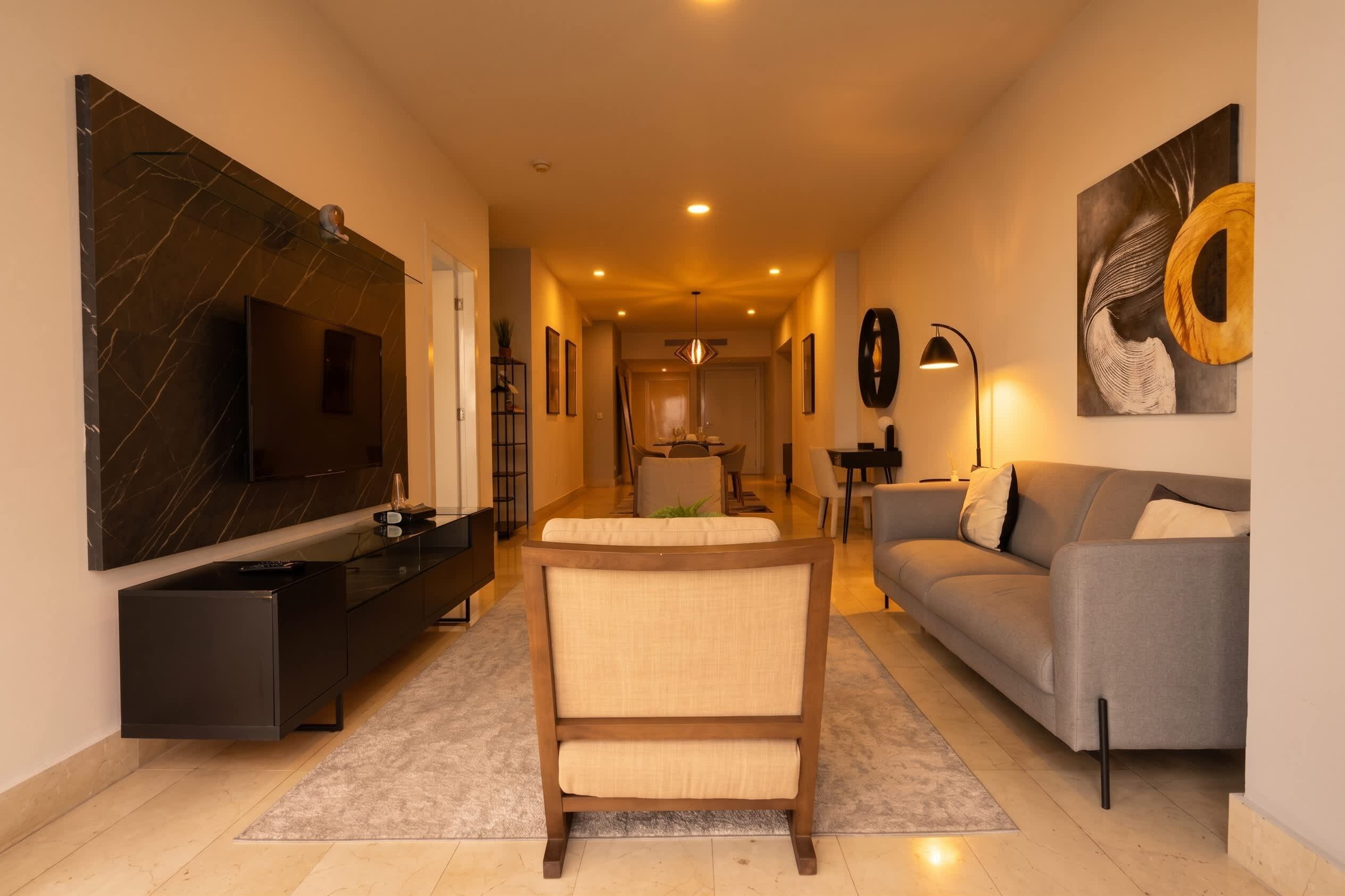 A modern living room with a sofa, a TV, and a dining area.