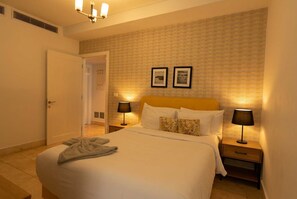 Een hotelkamer met een bed, twee bedlampen, een deur en een muur met een structuur.