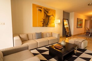 A modern living room with a sofa, coffee table, and a large painting on the wall. - 13 E, Apartamento en YOO con vista al mar y 2 dormitorios (Panamá)