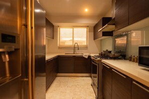 A compact kitchen with a window, stainless steel appliances, and dark cabinetry. - 13 E, Apartamento en YOO con vista al mar y 2 dormitorios (Panamá)