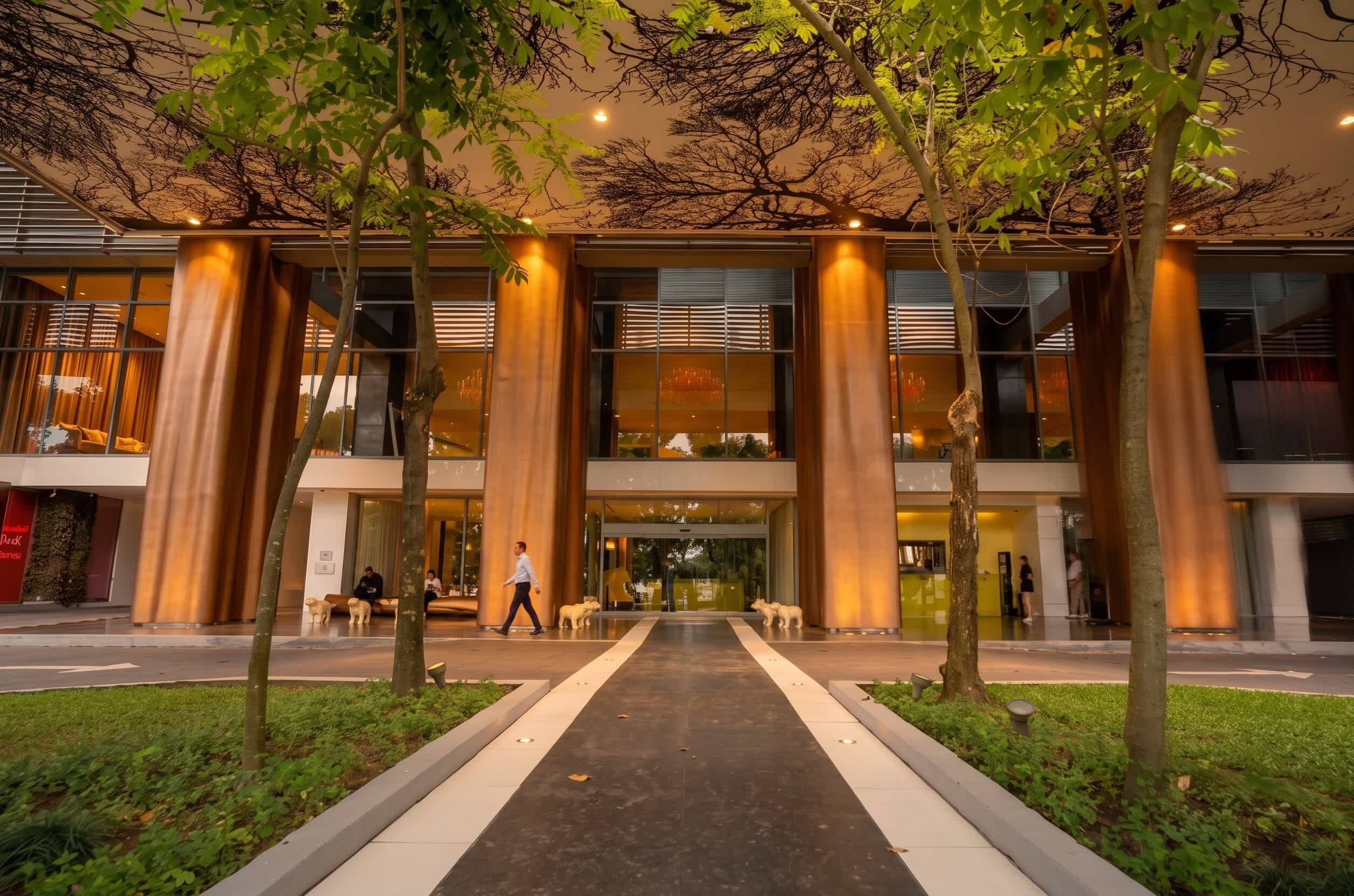 A modern building with large glass windows, a central entrance, and a pathway leading to the entrance.
