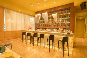 A bar area with a marble counter, multiple bar stools, and a wall of liquor bottles. - Apartamento 14J en YOO, Vista al mar con 2 recámaras (Panamá)
