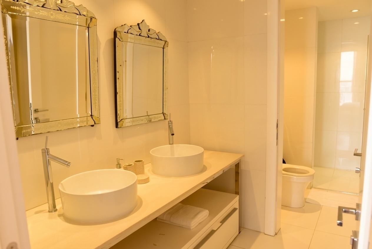 Een moderne badkamer met twee wasbakken, een douche en een toilet.