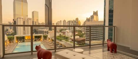 A rooftop terrace with a pool, seating area, and a view of the city skyline.