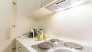 A compact kitchen with a stove, a kettle, and a coffee maker on the countertop. - AP4 - Apartment in the heart of Milan (Milano)