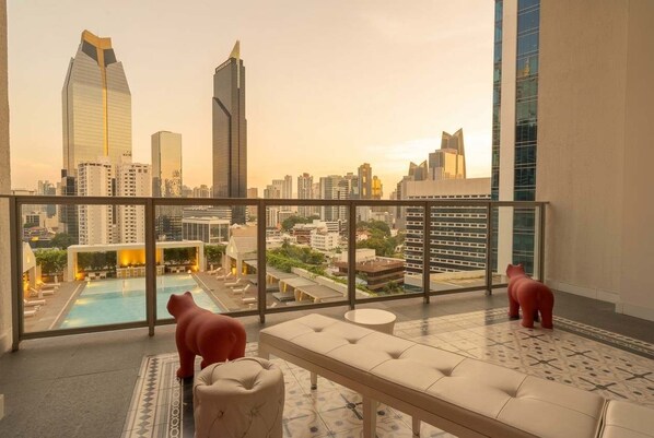 Terraço no telhado com piscina, área de estar e vista para o horizonte urbano.