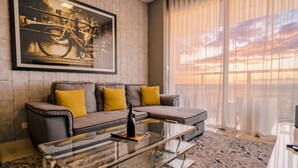 Ein modernes Wohnzimmer mit einer Couch, einem Glastisch und einem großen Fenster mit Vorhängen.