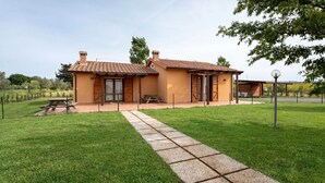 Une maison à deux étages, avec un toit recouvert de tuiles, une allée pavée et une cour clôturée.