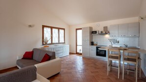 Une cuisine moderne avec des meubles blancs, un four à micro-ondes et un coin repas doté de chaises en bois.