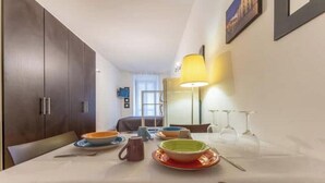 Un coin repas avec une table dressée pour deux personnes, une lampe et une vue sur la pièce.