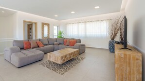 Una sala de estar moderna con un sofá modular, una mesa de centro de madera y un televisor sobre un mueble de madera.