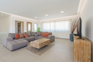 Ein modernes Wohnzimmer mit einer Eckcouch, einem Holztisch und einem Fernseher auf einem Holzständer.