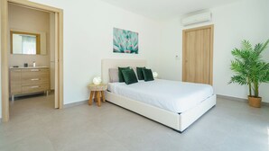 Un dormitorio con cama, mesita de noche, espejo, aire acondicionado instalado en la pared y una planta en maceta.