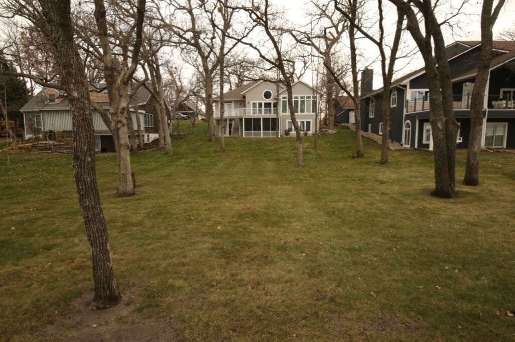 A residential area with multiple houses, a grassy yard, and leafless trees.