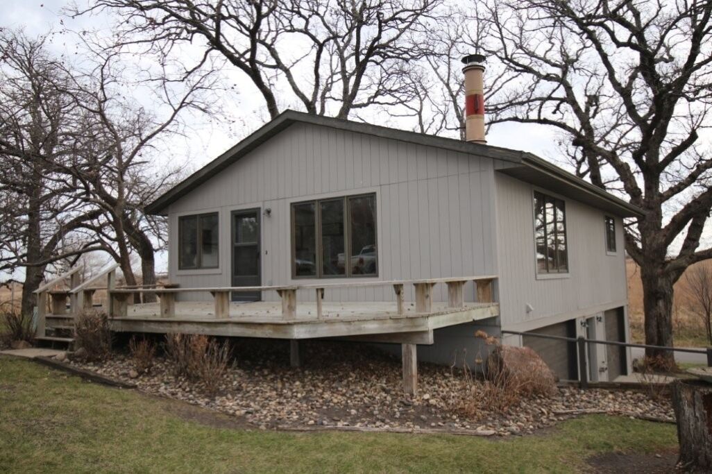 A single-story building with a flat roof, a chimney, and a deck.