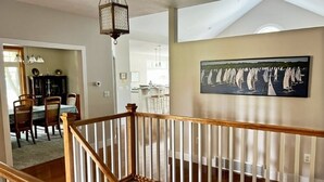 Una escalera con barandillas de madera que conduce a un comedor con mesa y sillas.