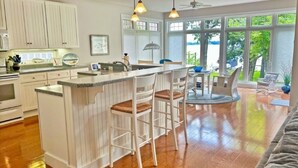 Una cocina con una isla central, muebles blancos y un amplio ventanal que ofrece vistas al exterior.
