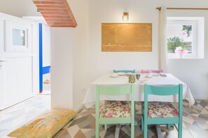 Un coin repas avec une table dressée pour deux personnes, un luminaire fixé au mur et une fenêtre donnant sur un beau paysage.