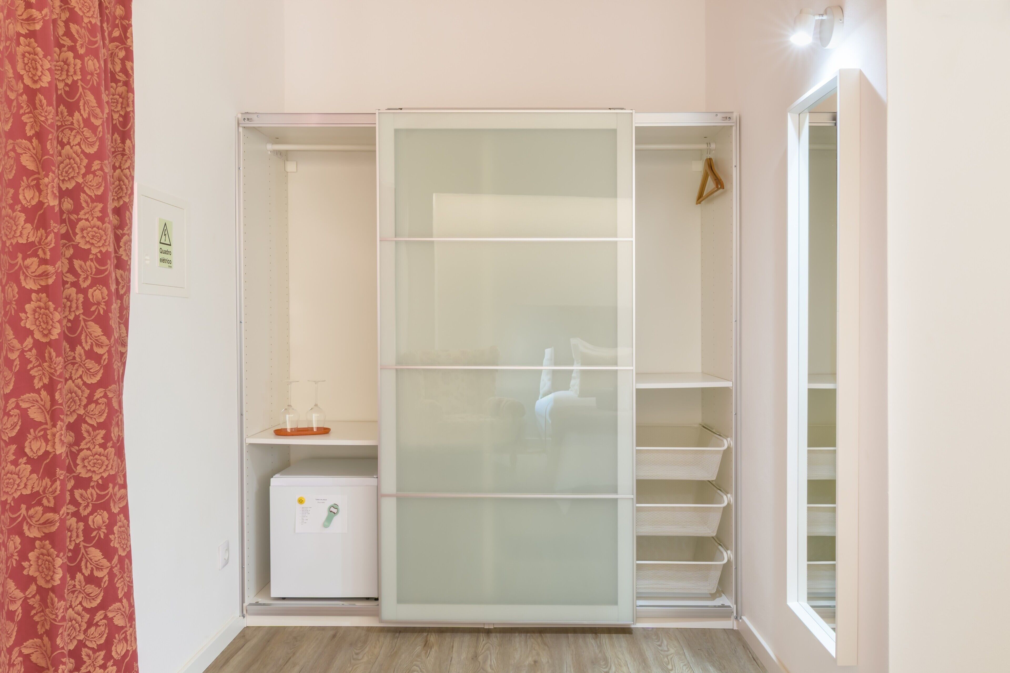 Un vestidor con puertas correderas, un pequeño electrodoméstico blanco y una percha.
