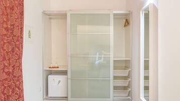 Un vestidor con puertas correderas, un pequeño electrodoméstico blanco y una percha.