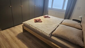 Makuuhuoneessa on sänky, työpöytä, tuoli ja ikkuna, jossa on verhot.