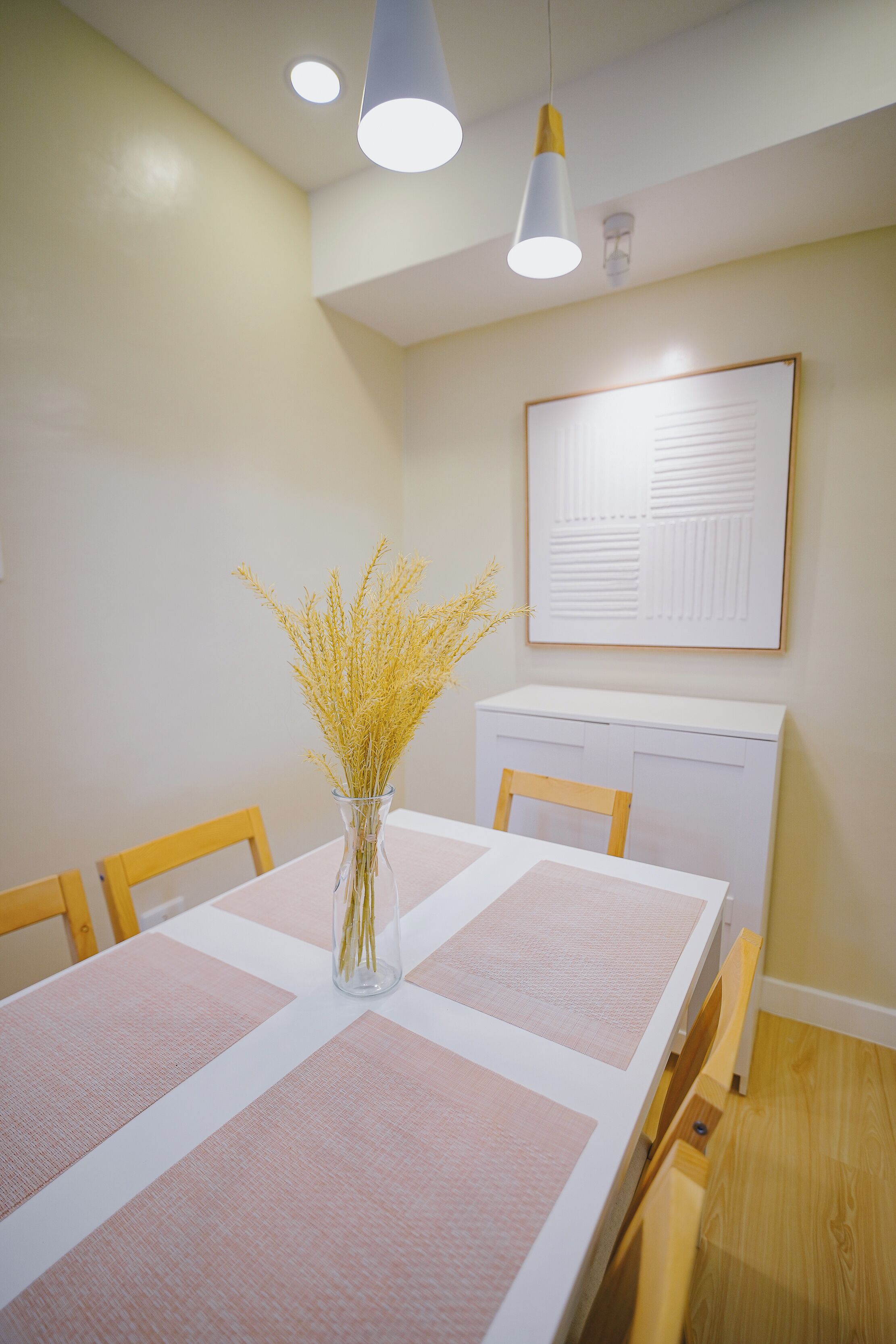 Ein Essbereich mit Tisch, Stühlen, einer Vase mit Trockenpflanzen und einer Tafel an der Wand.
