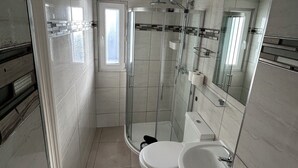 Casa de banho moderna com chuveiro envidraçado, sanita e lavatório.